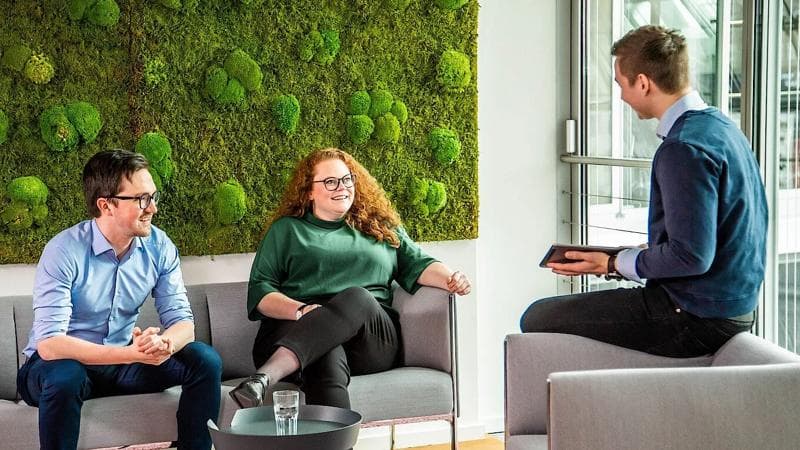 Körber employees sitting in a sofa talking about how to decrease CO2 emissions.