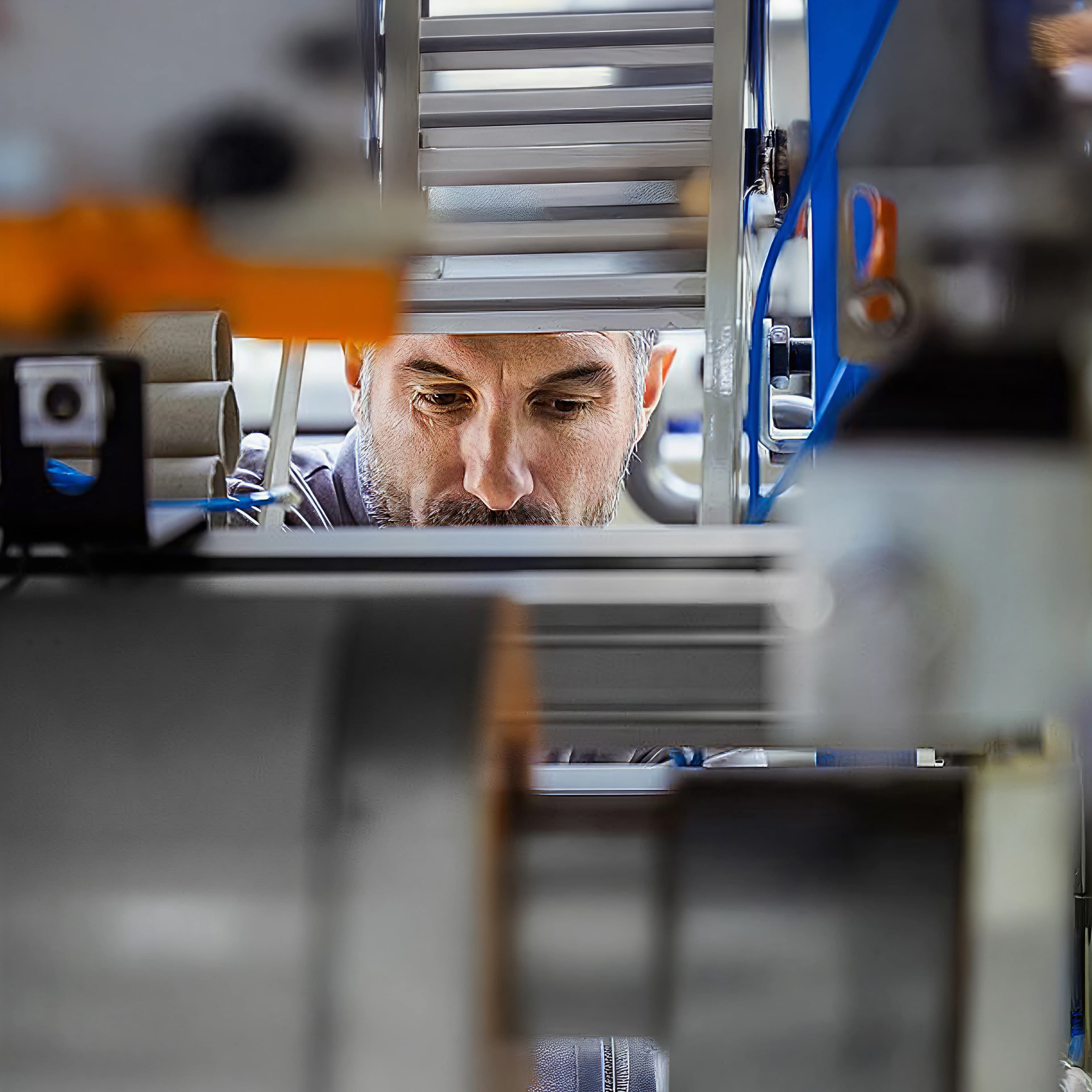 Photograph of a man seen through a gap in a machine