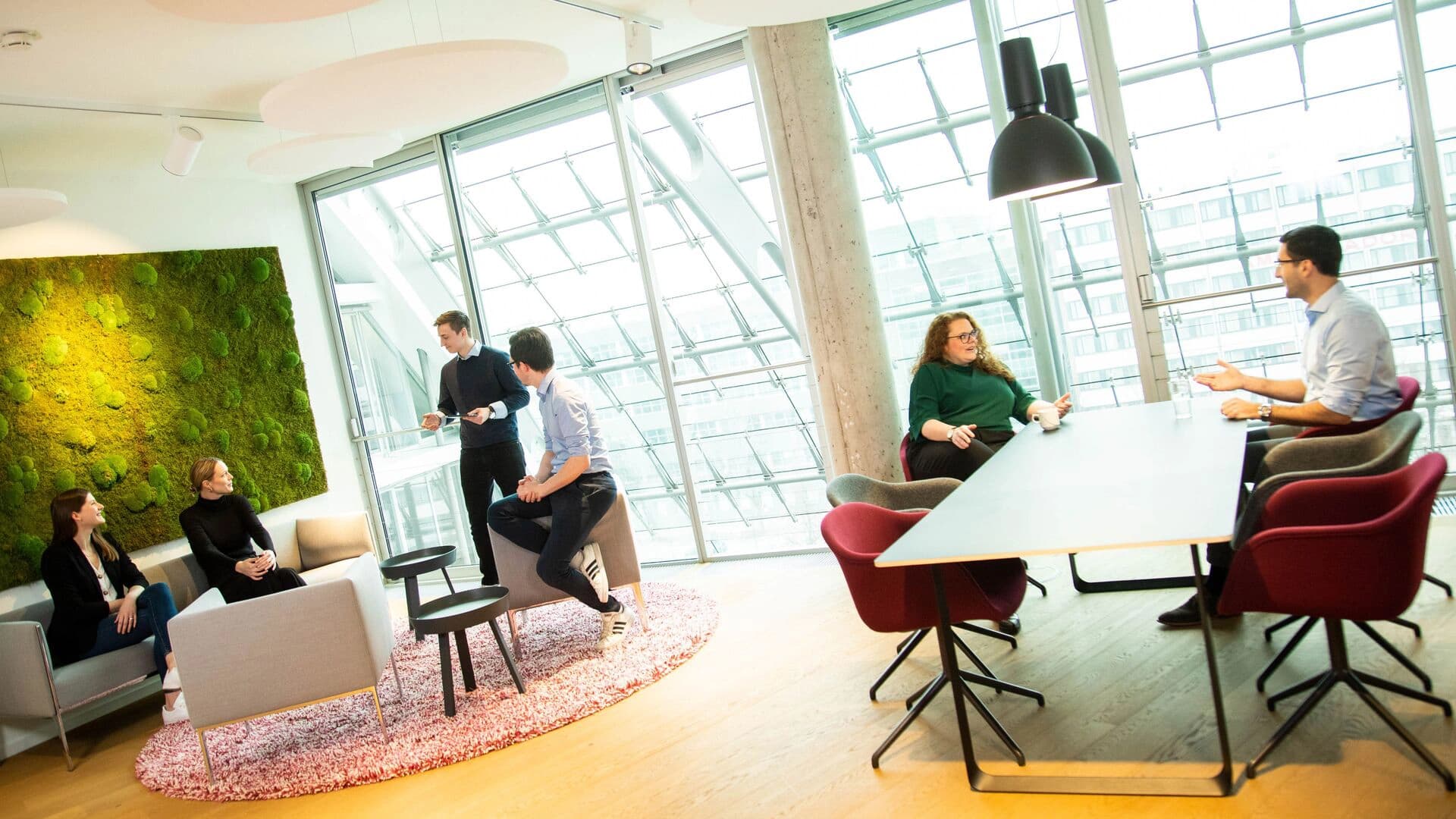 A group of people engaged in discussion while seated around a conference table in an office setting.