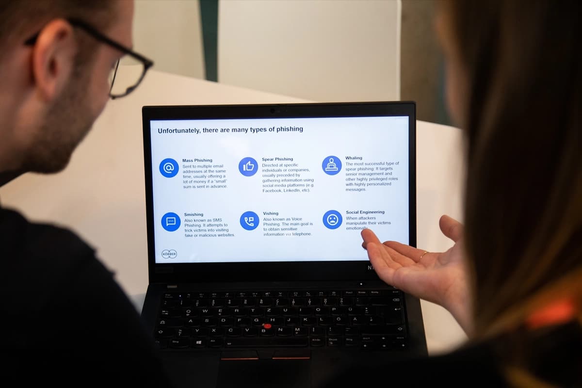 A man and woman examine a laptop displaying a diagram related to artificial intelligence and information security.