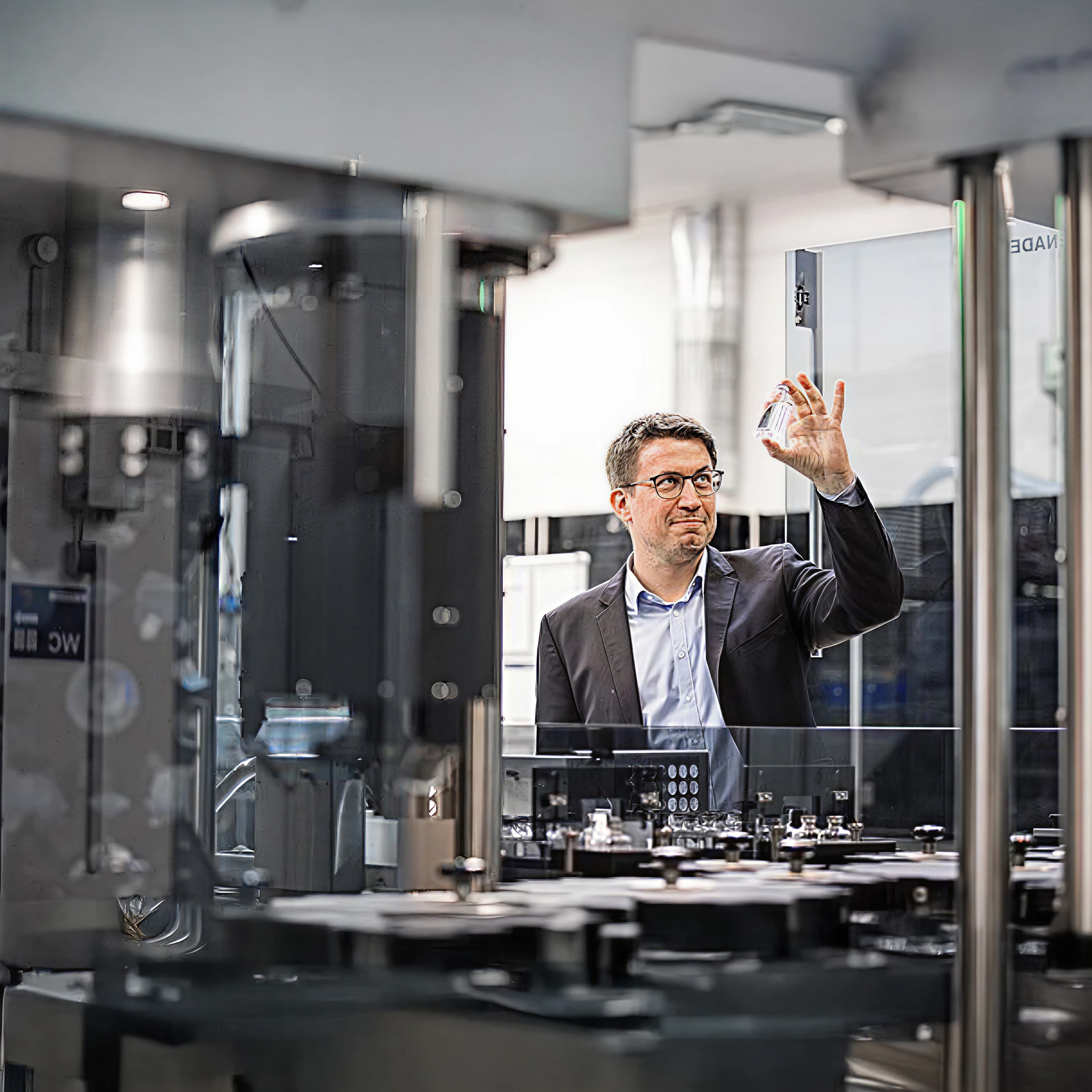 Man holding a small glass bottle up in a processing facility