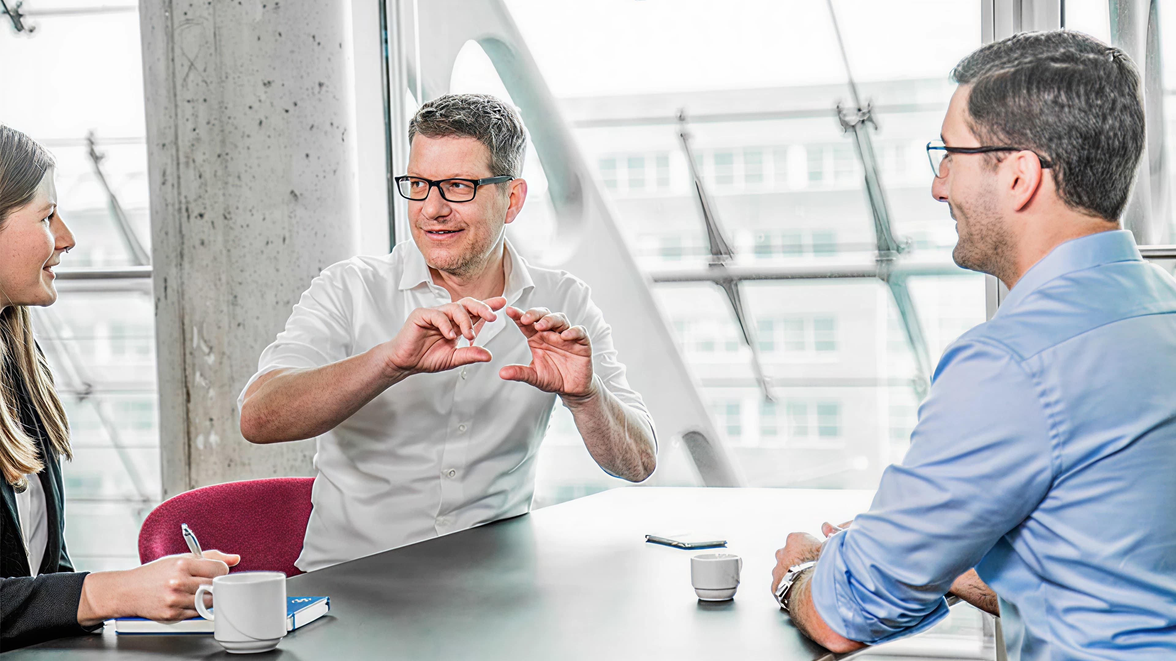 Two men and a woman talking in a meeting room