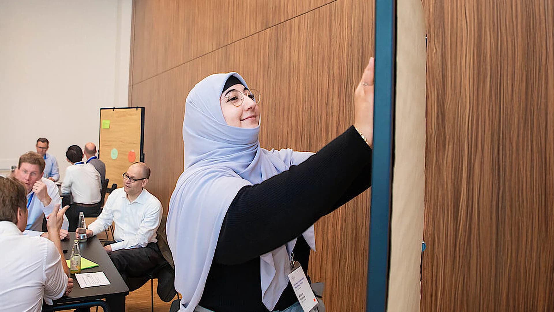 Woman writing on a white board in an office space.