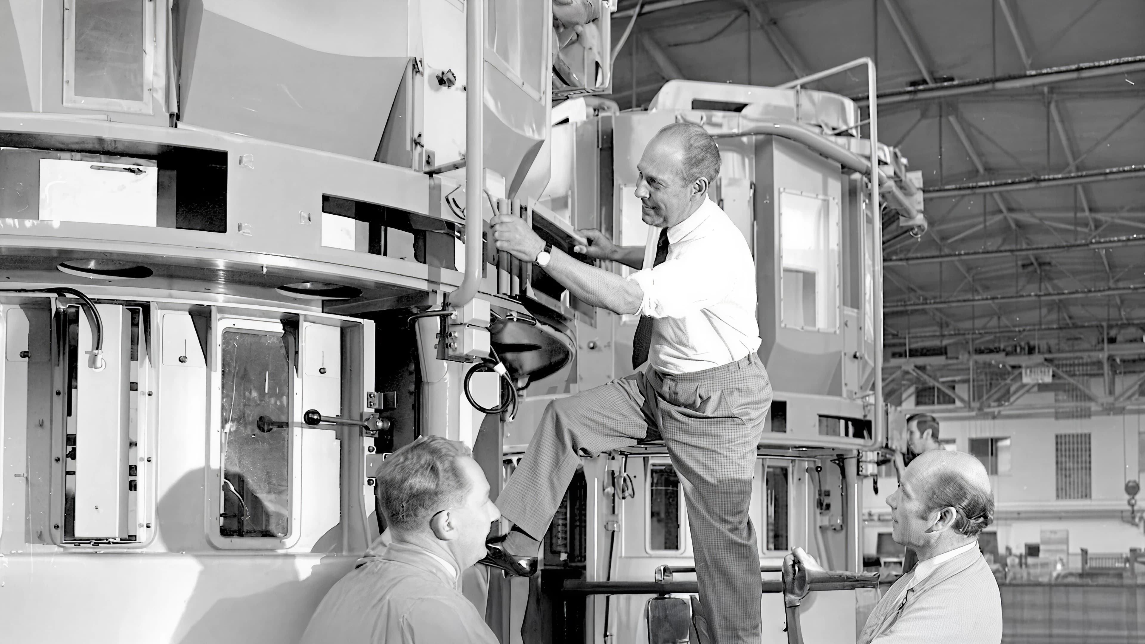 Black and white photo of three men inspecting machinery