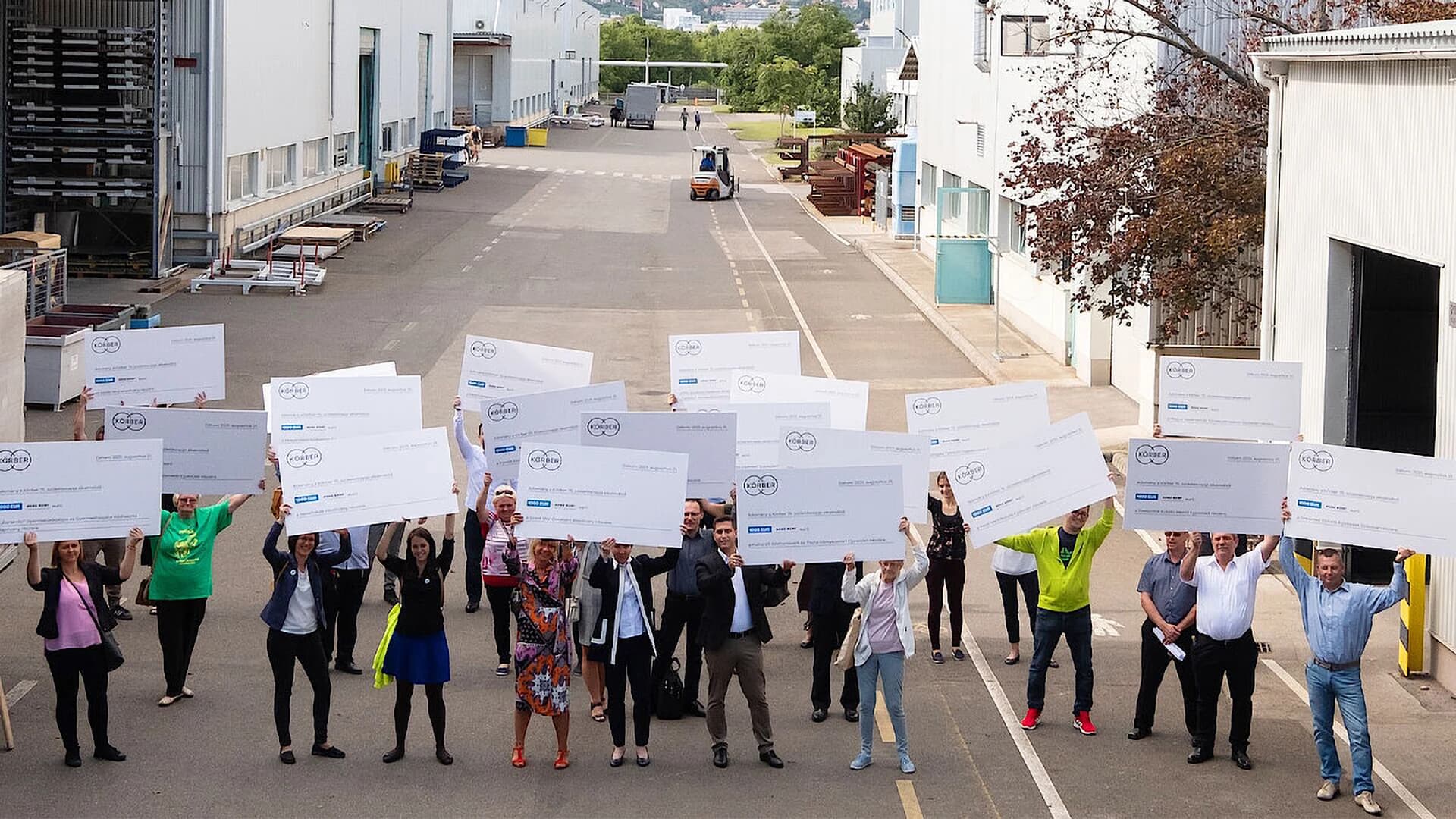 A group of people in an industrial area celebrating an achievement or donation.