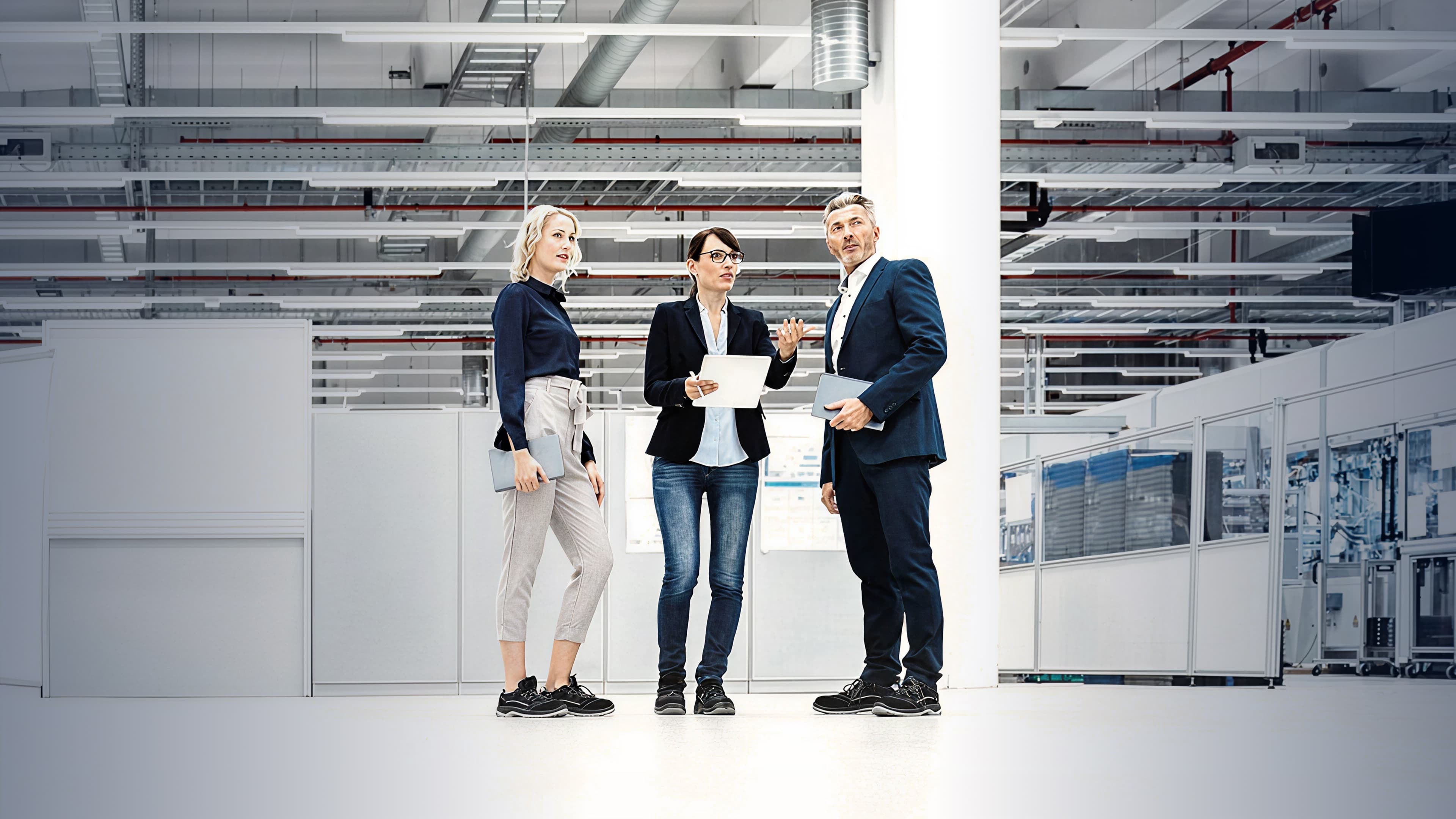 Three people standing in a large, industrial room