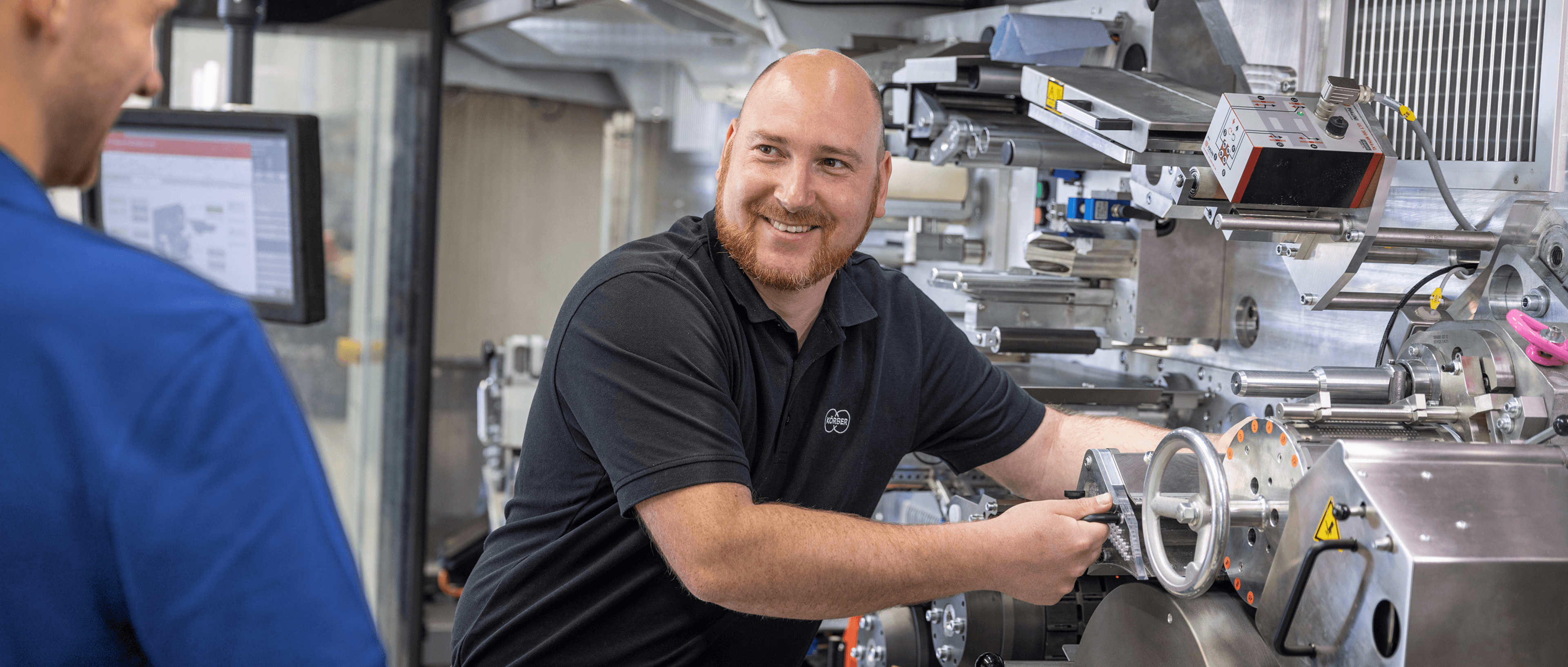 Körber technician smiling and servicing a machine