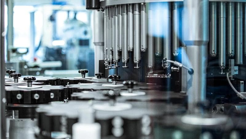 A detailed view of an inspection machine from Körber Pharma producing bottles in a factory setting.