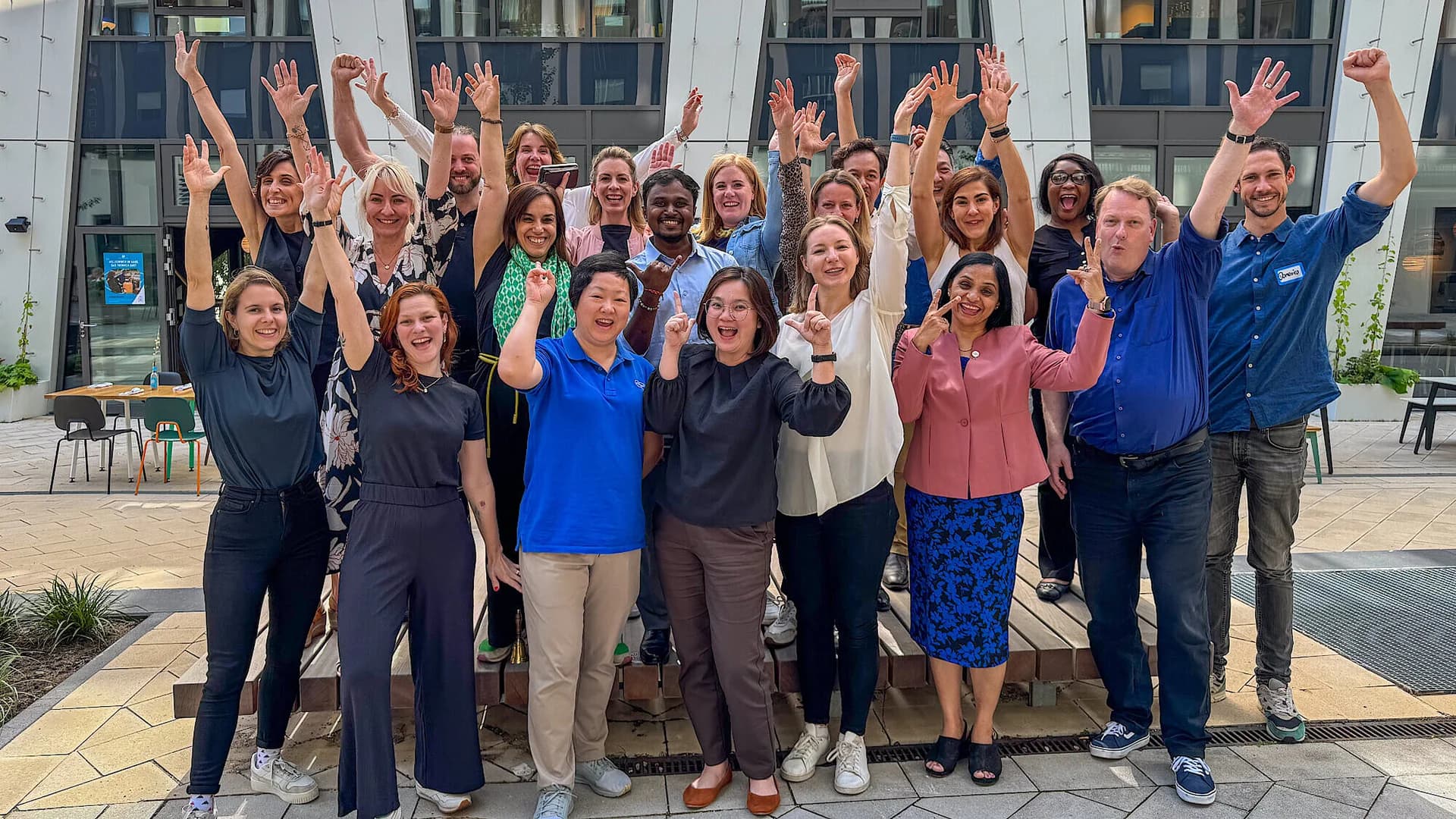 A group of diverse individuals smiling and posing together in front of a large building.