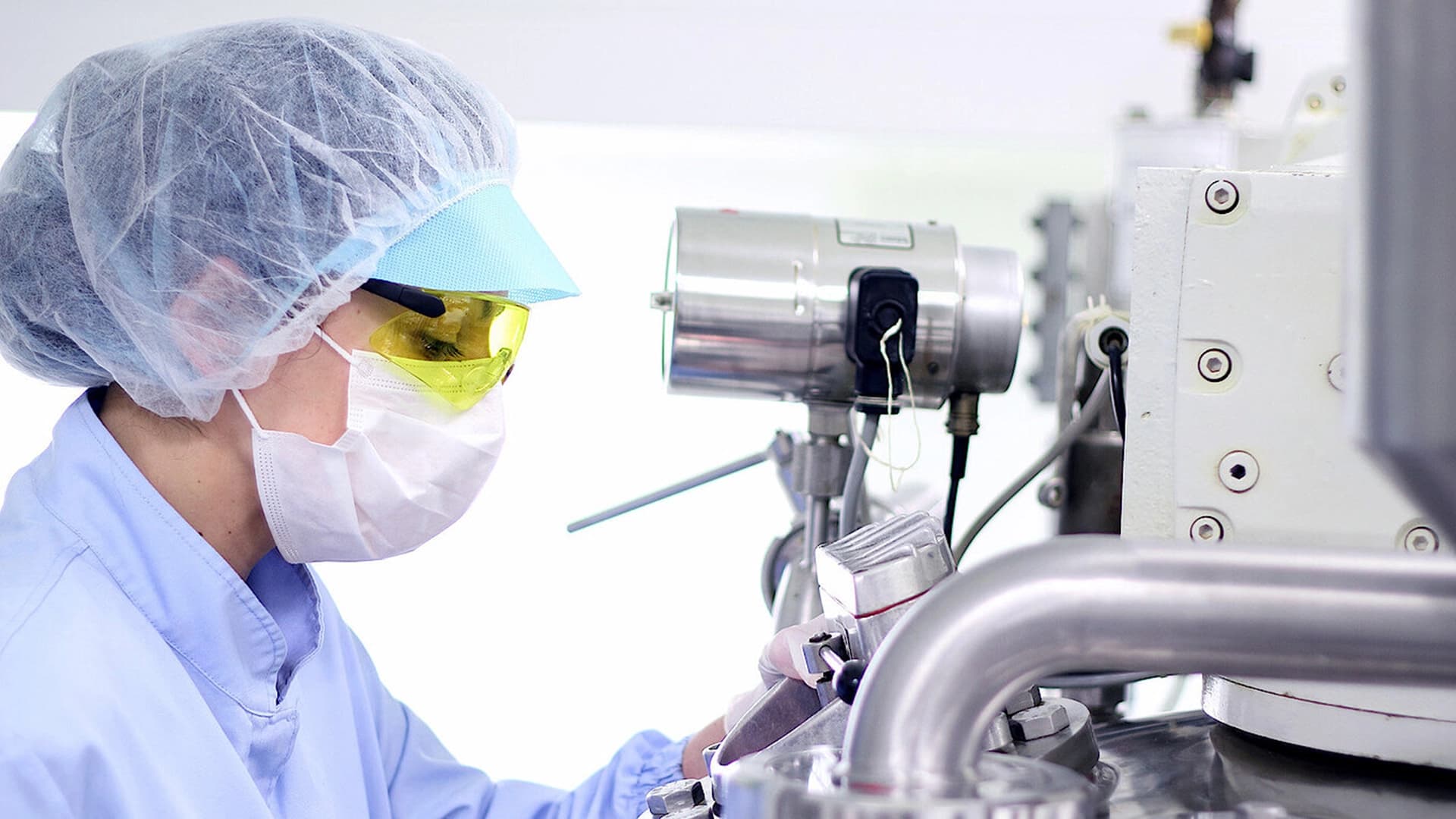 Woman with a white lab coat and glasses operating a machine.