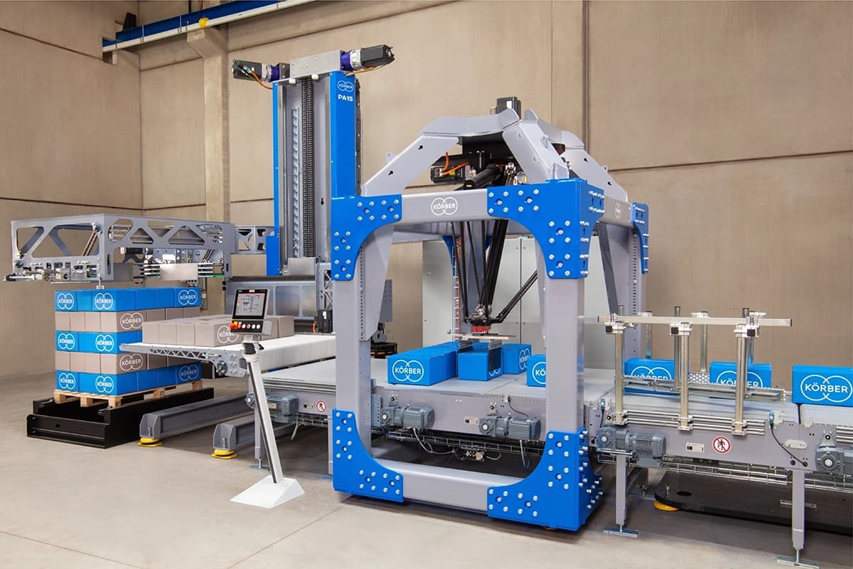 A Körber PA15 layer palletizer machine assembling boxes in a factory setting.