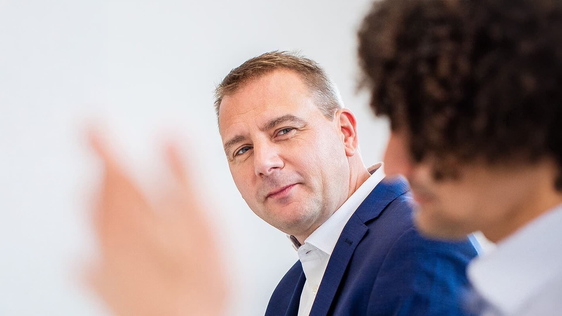 Man wearing a blue suit looking at a person out of focus