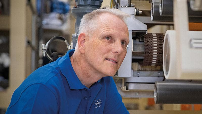 Körber employee in front on machines facing the camera, but looking up.