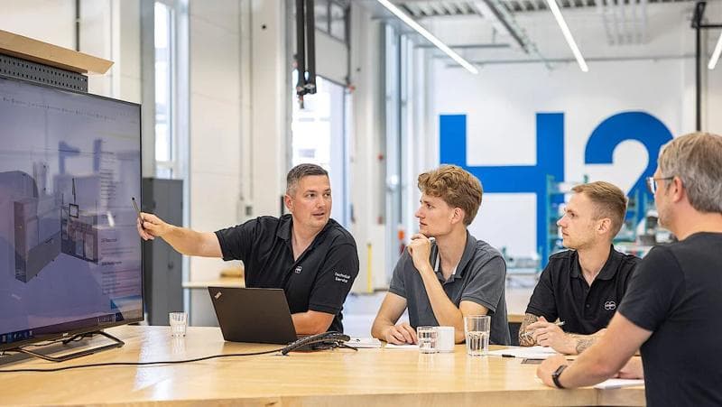 Körber's employees meeting around a table discussing digital transparency and governance.