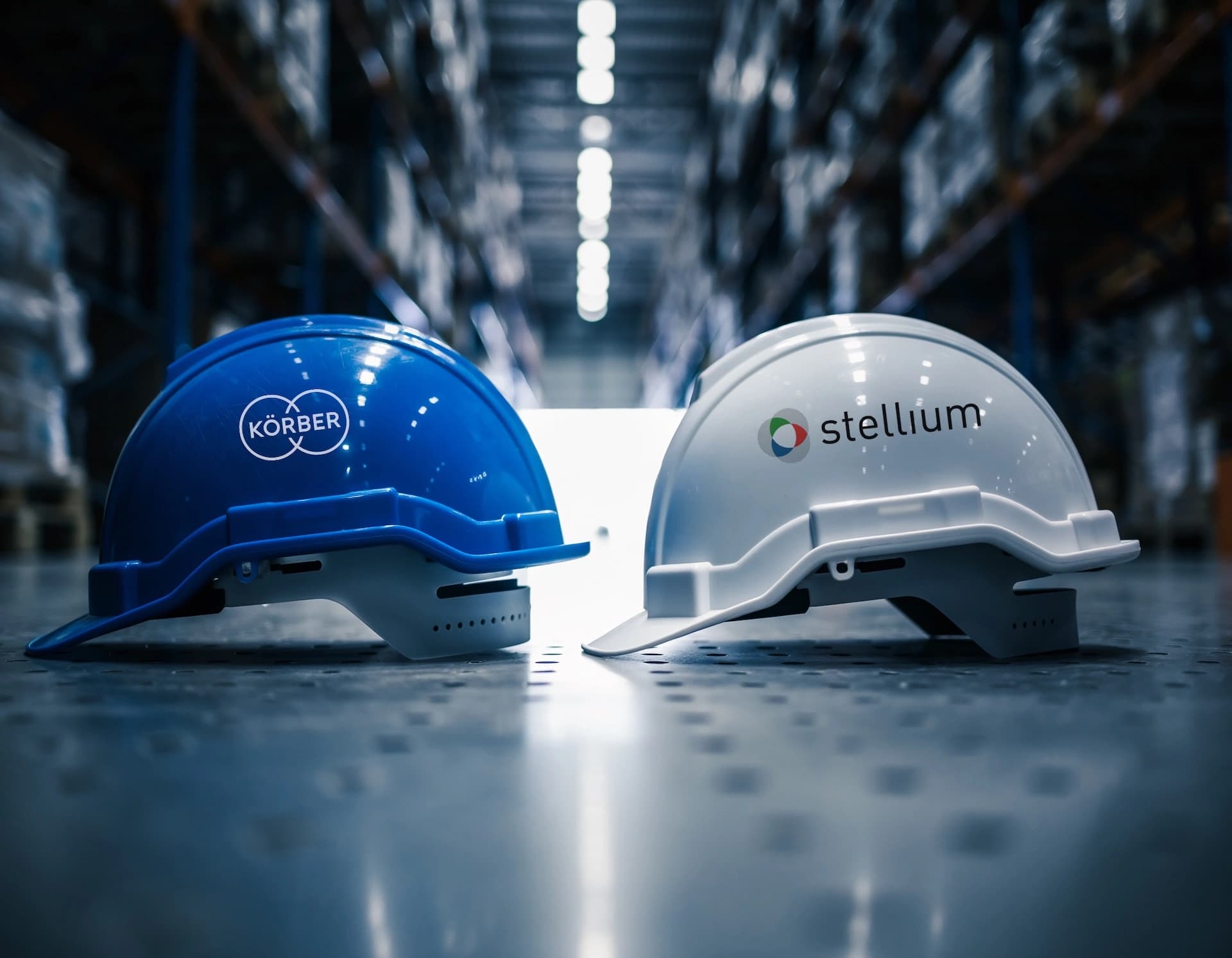 Two hard hats from Körber and Stellium positioned on a warehouse floor