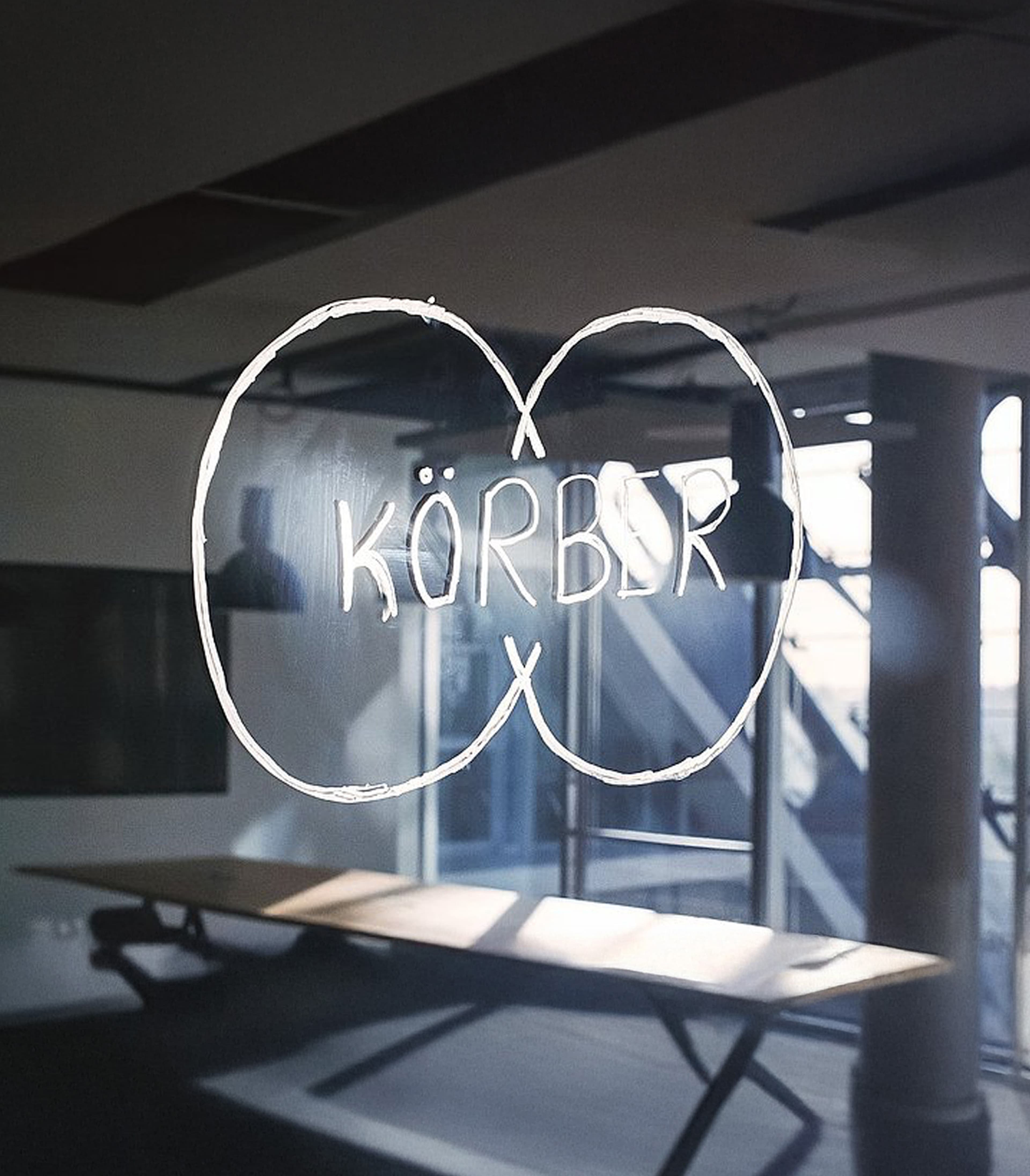 Körber logo handdrawn in white pen on a glass window