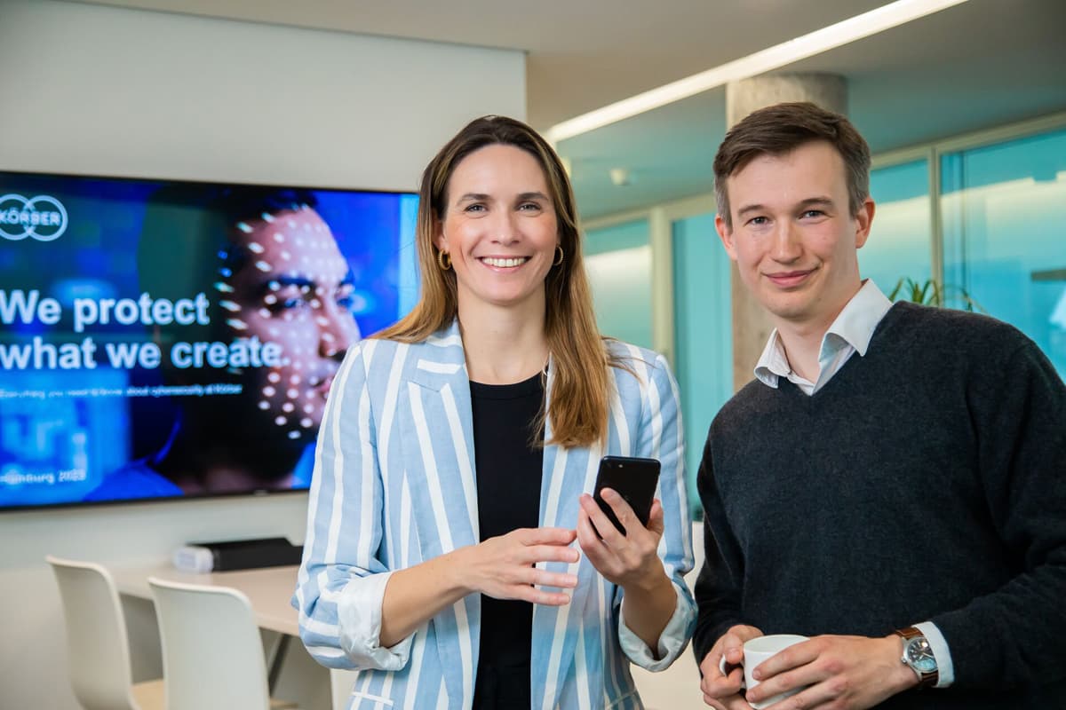 Two individuals standing together in front of a television screen