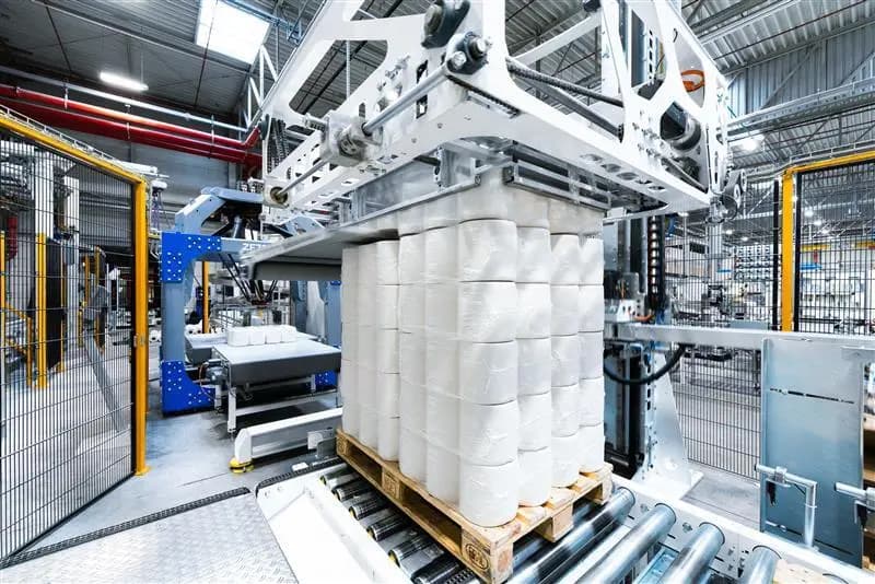 The PA15 layer palletizer by Korber is actively assembling bottles of water for packaging in a manufacturing facility.