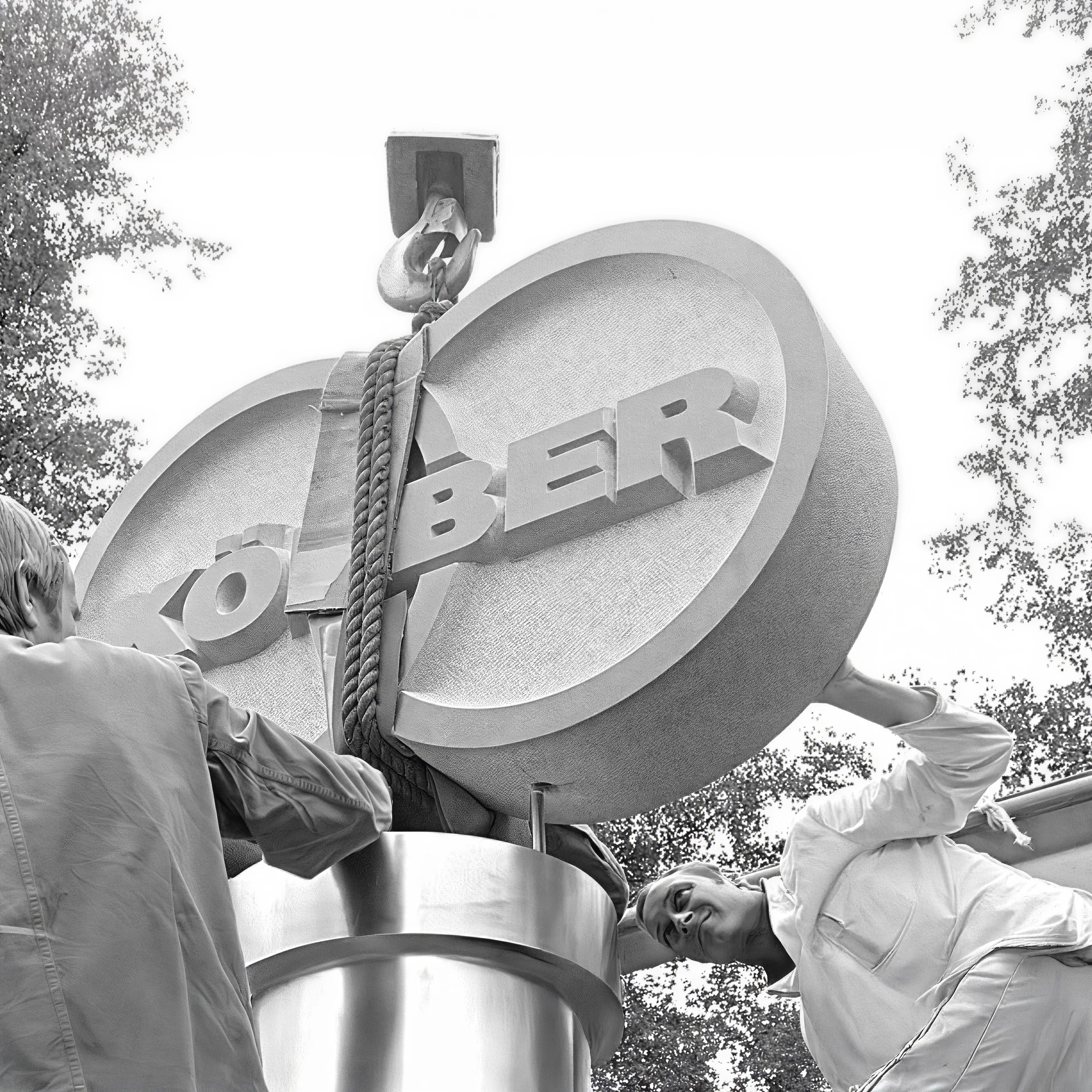 Black and white photo of a Körber sign being fixed in place