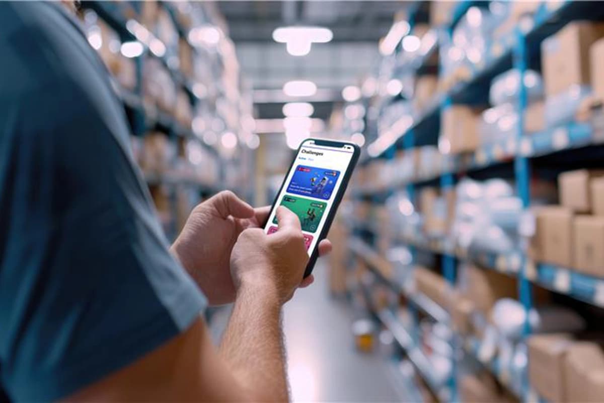 Worker in a warehouse scans items with a mobile device, utilizing gamification to improve productivity and engagement.