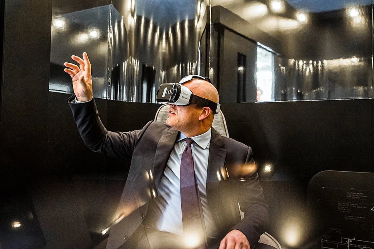 A suited man uses a virtual reality headset, exploring a digital world through immersive technology.