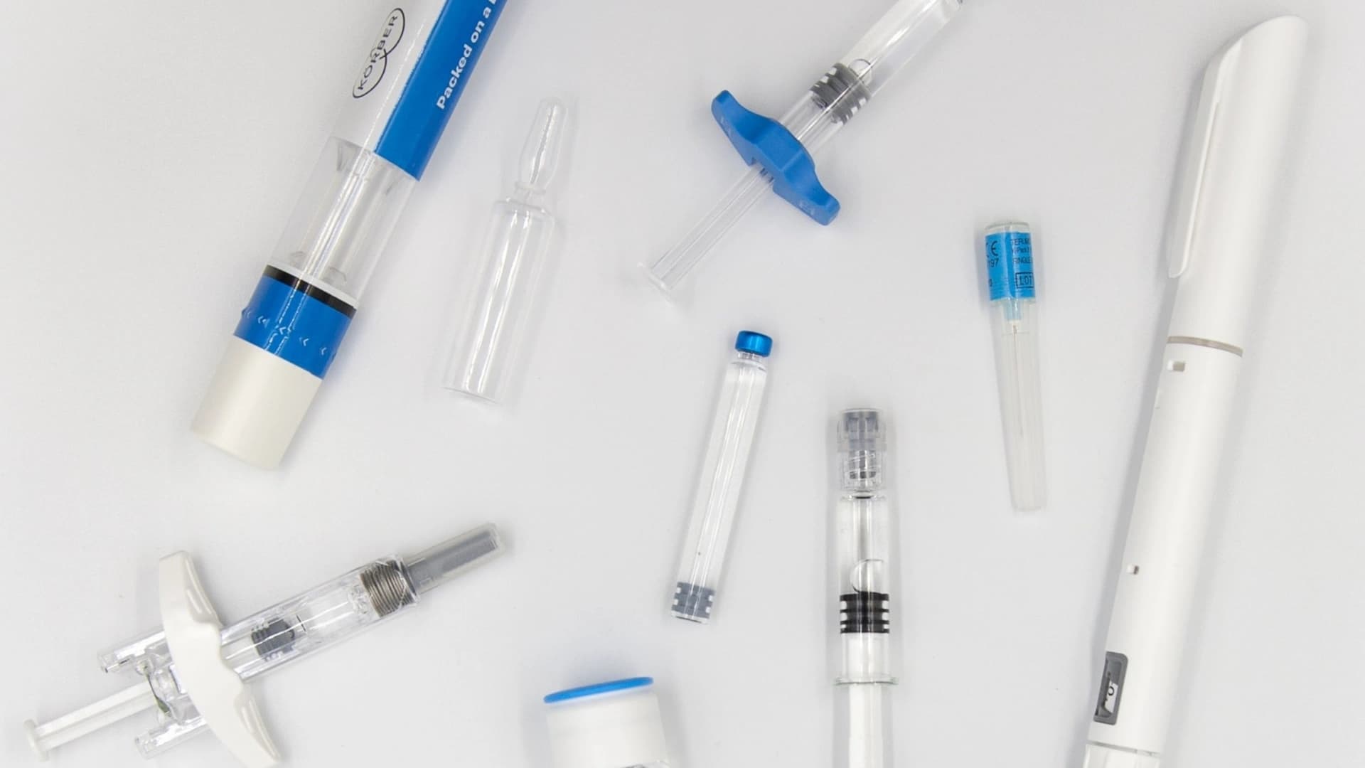 Picture of syringes, vials, pens and autoinjectors laid out on a table.