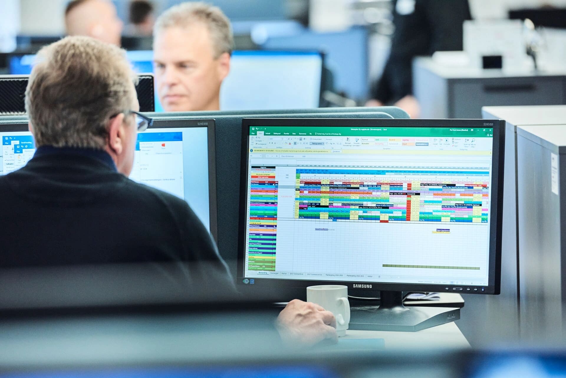 A Körber worker at a desk with two monitors, focused on supply chain add-ons
