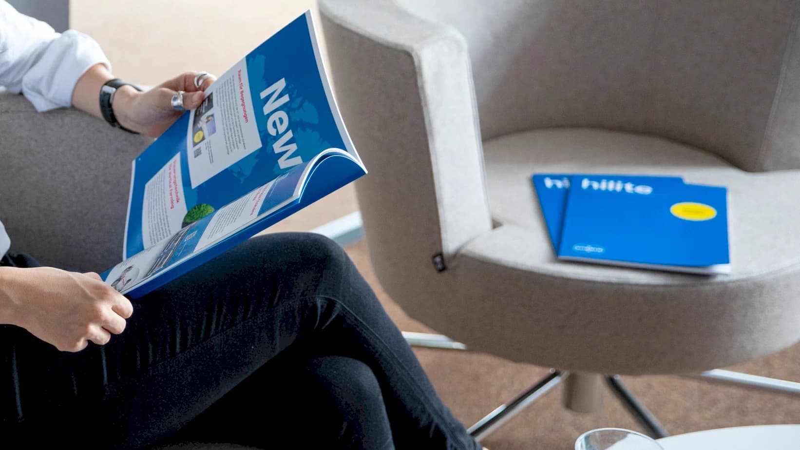 A person sitting in a chair, reading Hilite magazine.