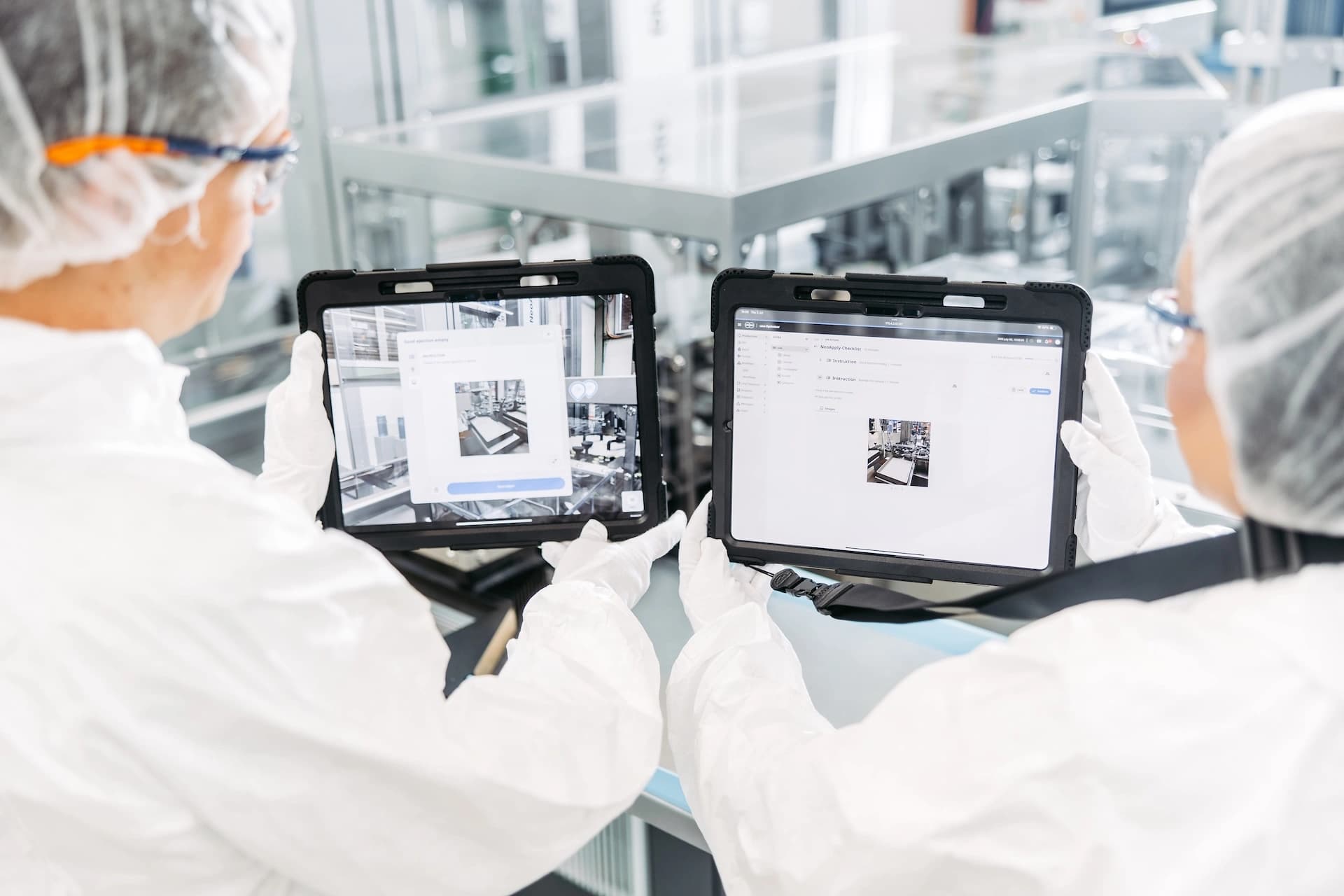 Two man standing in front of a Körber full line packaging machine, holding a tablet.