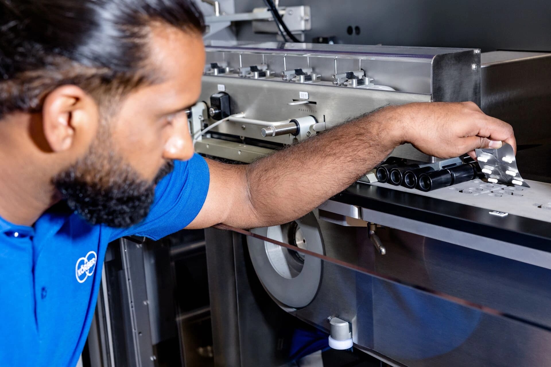 Hand adjusting a blister package on a machine.