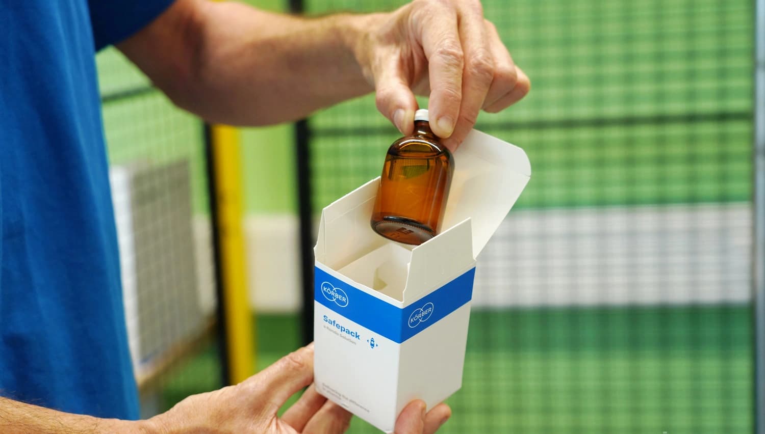 Picture of a Körber employee showing a folding carton package.