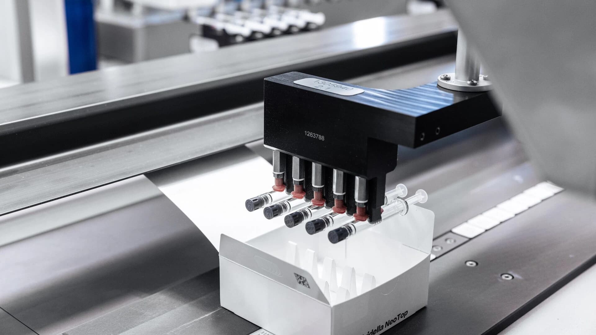 Close up of a topload machine packaging syringes.
