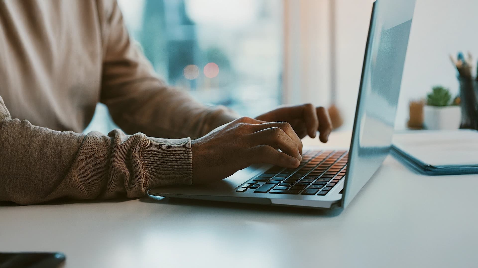 Close-up of hands typing on a laptop keyboard.