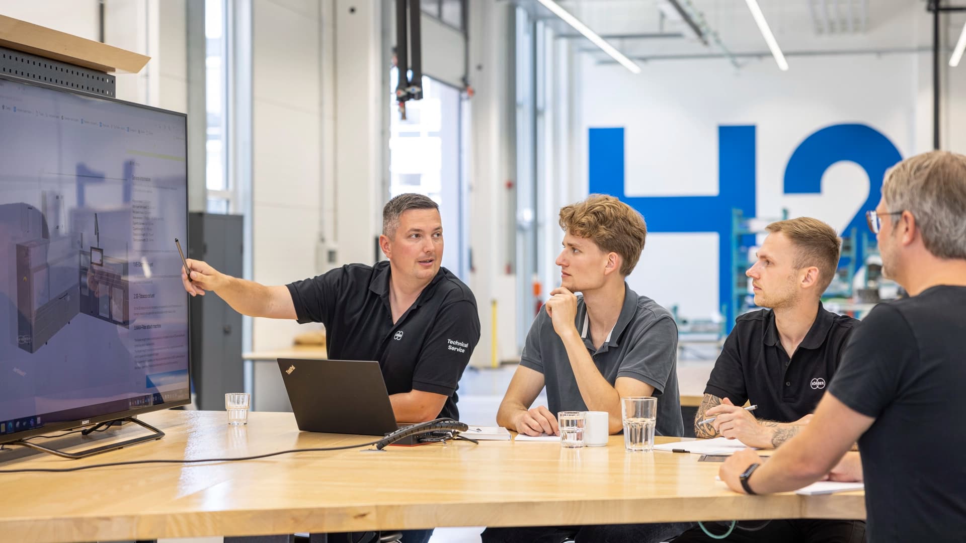 Körber employees at a meeting looking at a TV screen.