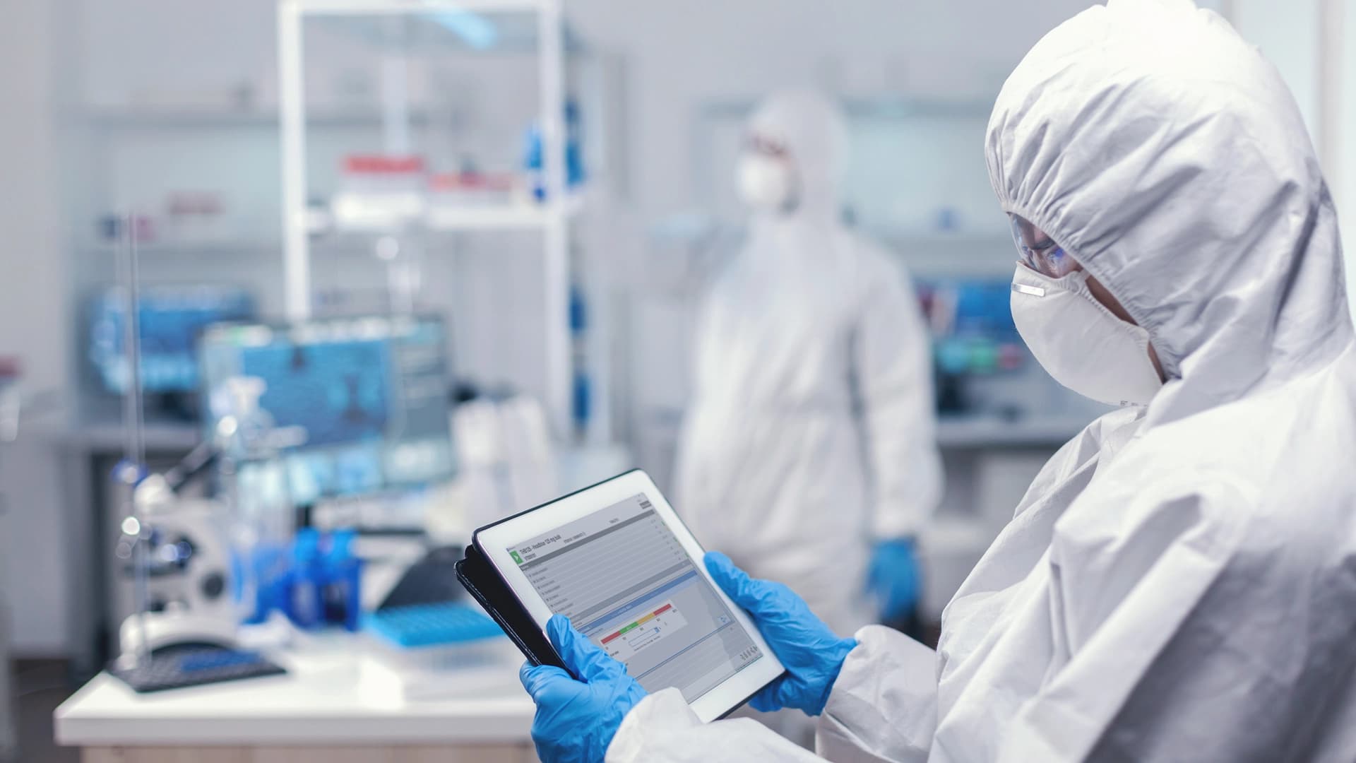 Körber employee holding a tablet wearing protective chemical gear.