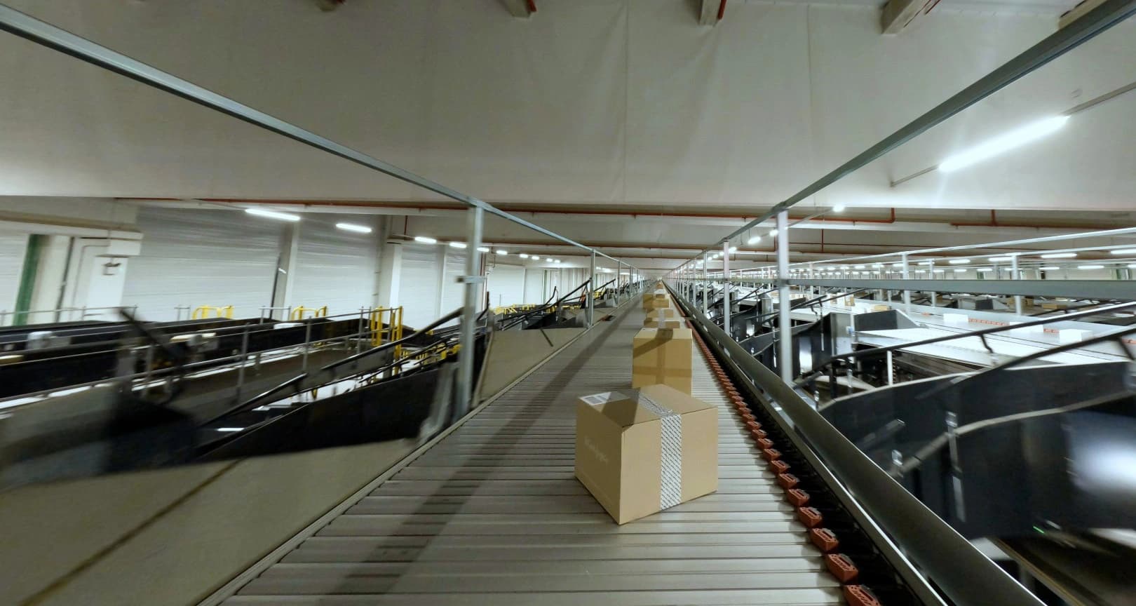 A conveyor belt transporting several boxes in a GLS'warehouse