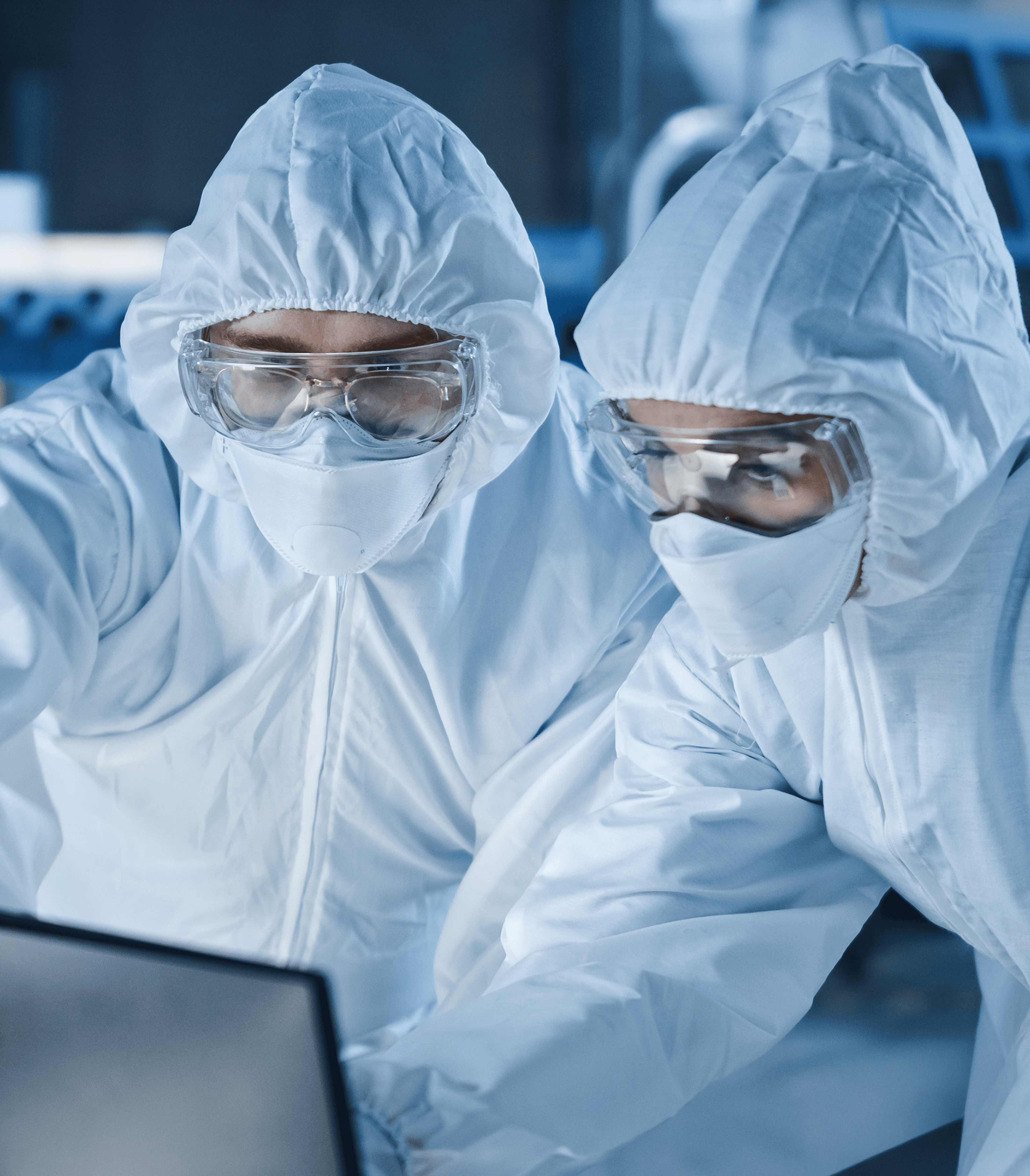 Two people wearing personal protective equipment looking at a laptop