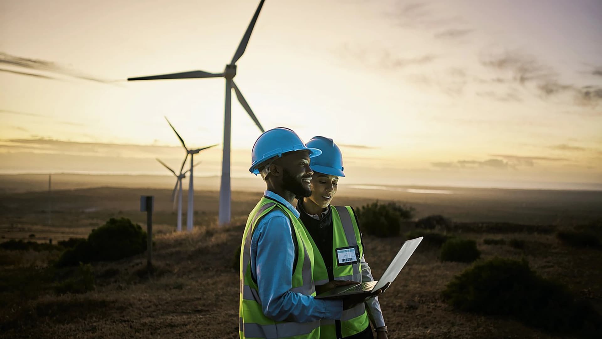 Environmental workers in a field with wind turbines.