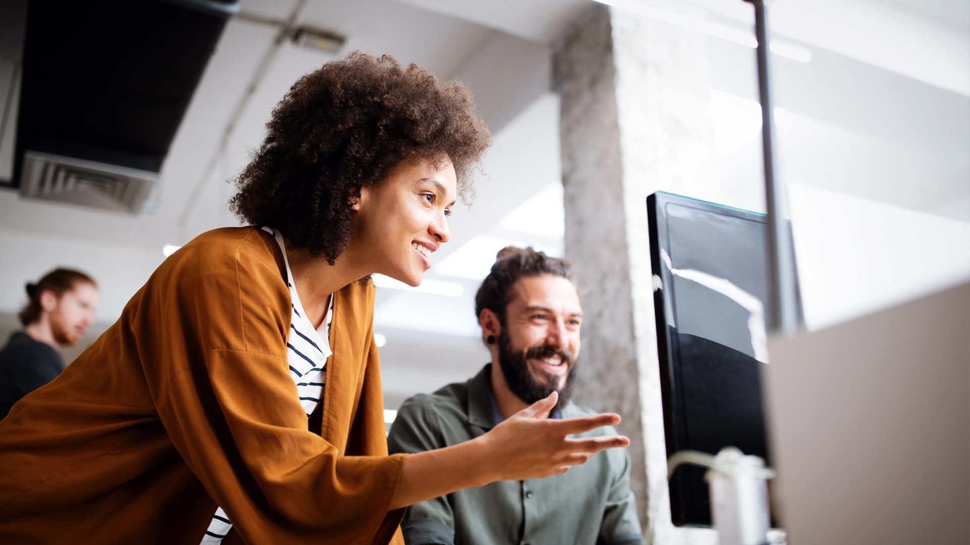 Two colleagues smiling and collaborating at a computer, reflecting a positive and inclusive work environment.