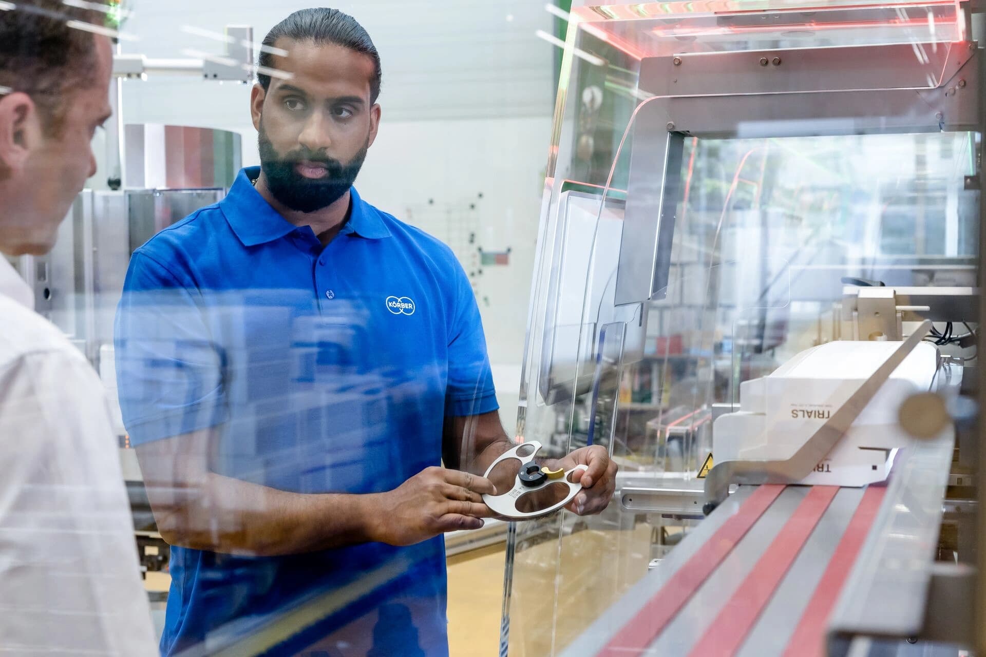 Two men are working together on a machine, concentrating on their mechanical task.